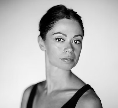 Ritratto in bianco e nero di una ballerina con sguardo intenso e capelli raccolti.