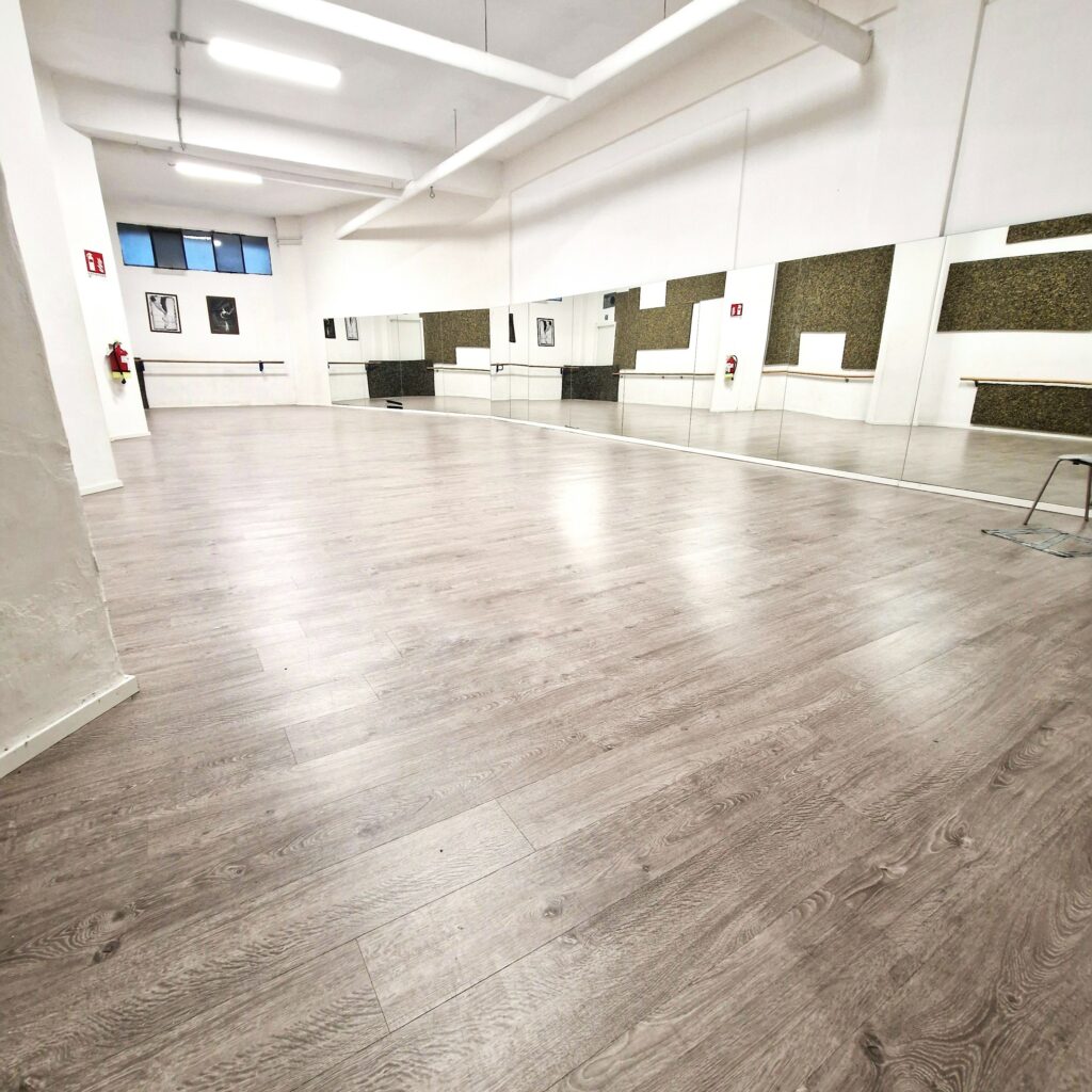 Spazio ampio e luminoso con pavimento in legno e grandi specchi alle pareti.